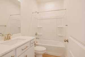 Full bath with vanity, washtub / shower combination, and light wood finished floors