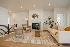 Living room featuring recessed lighting, light wood finished floors, and a glass covered fireplace