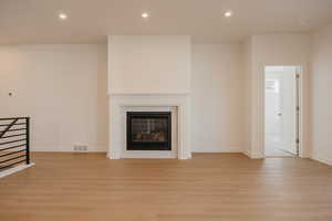 Unfurnished living room with light wood-style floors, recessed lighting, and a fireplace