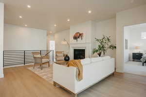 Living area with recessed lighting, light wood finished floors, and a glass covered fireplace