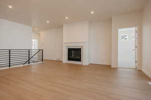 Unfurnished living room with recessed lighting, light wood finished floors, and a glass covered fireplace