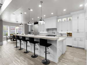 Kitchen featuring glass insert cabinets, light wood-style flooring, and hanging light fixtures