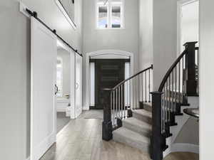 Entryway featuring a barn door, a high ceiling, and wood tiled floors