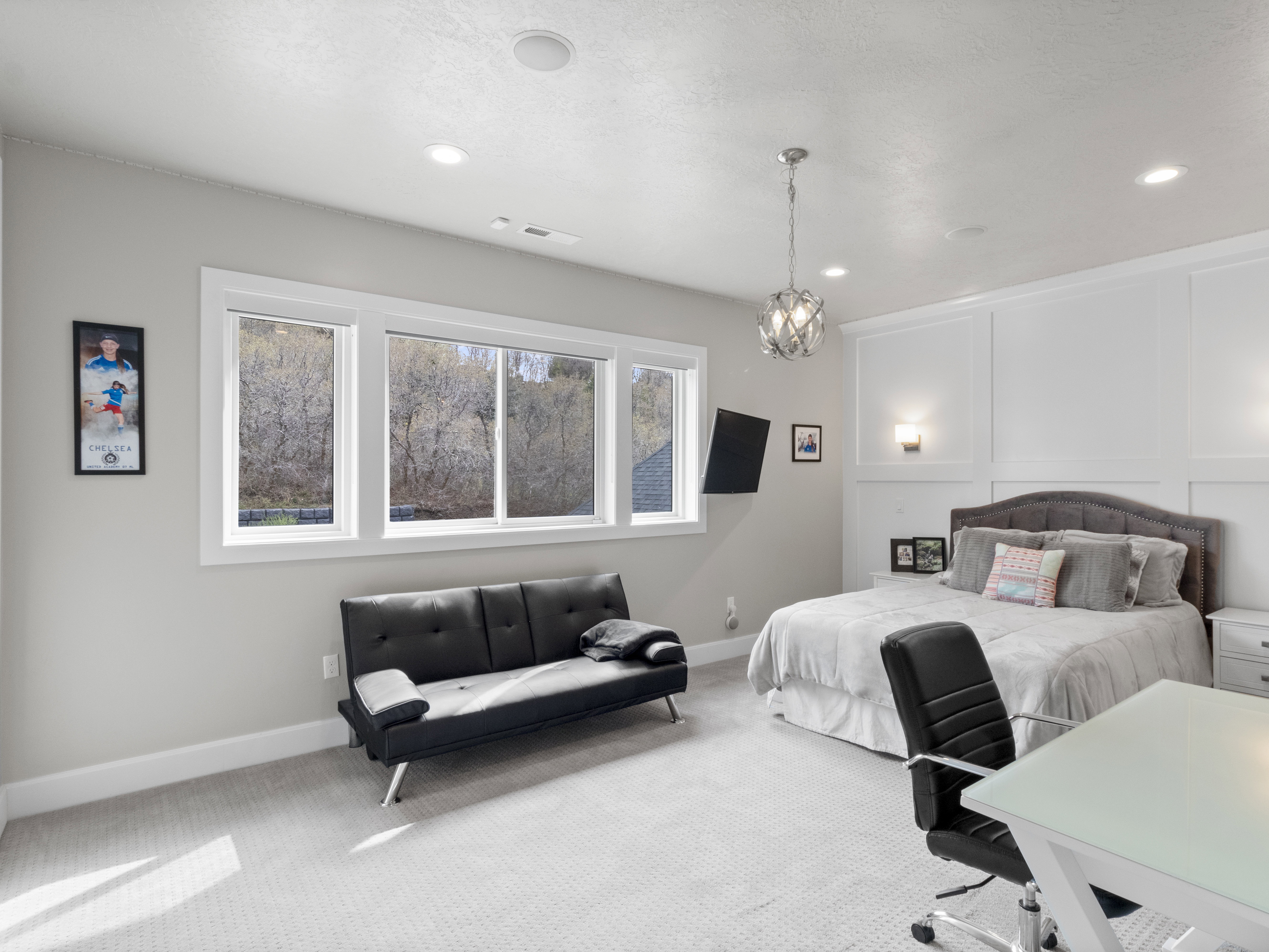 Bedroom with carpet, a decorative wall, and suspended lighting