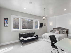 Bedroom with carpet, a decorative wall, and suspended lighting