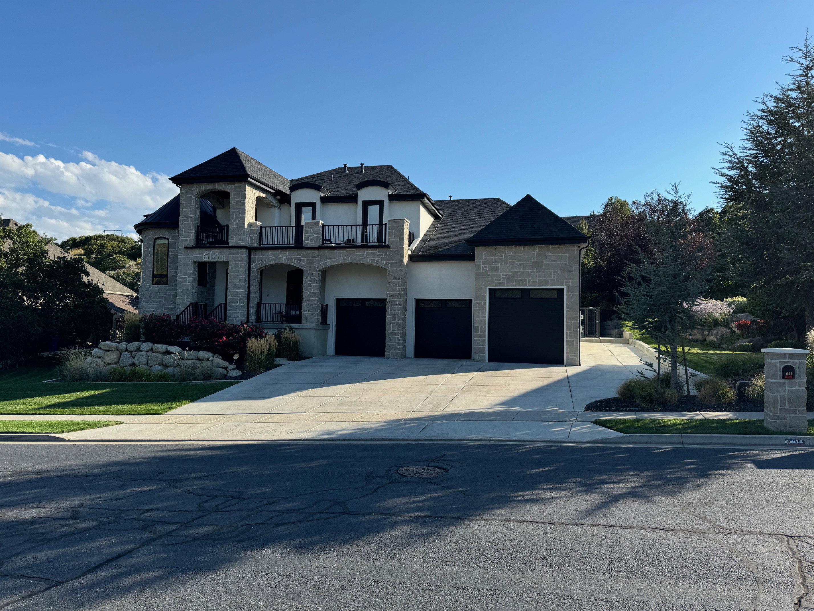 French country home featuring stone siding, a balcony, stucco siding, concrete driveway, and a garage