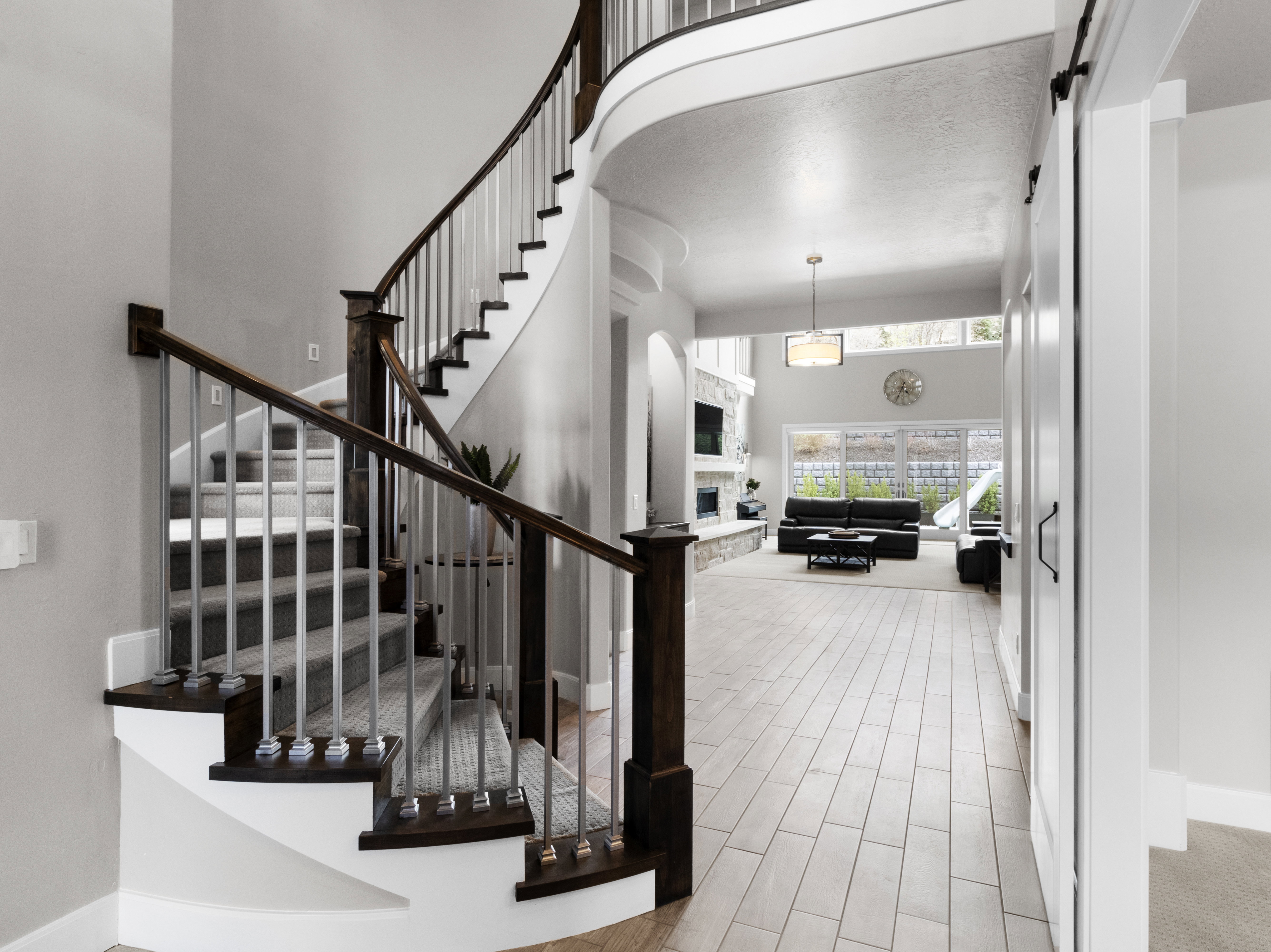 Staircase featuring a high ceiling, a stone fireplace, wood tiled floors, and arched walkways