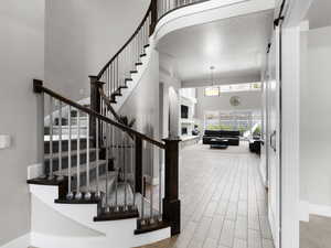 Staircase featuring a high ceiling, a stone fireplace, wood tiled floors, and arched walkways