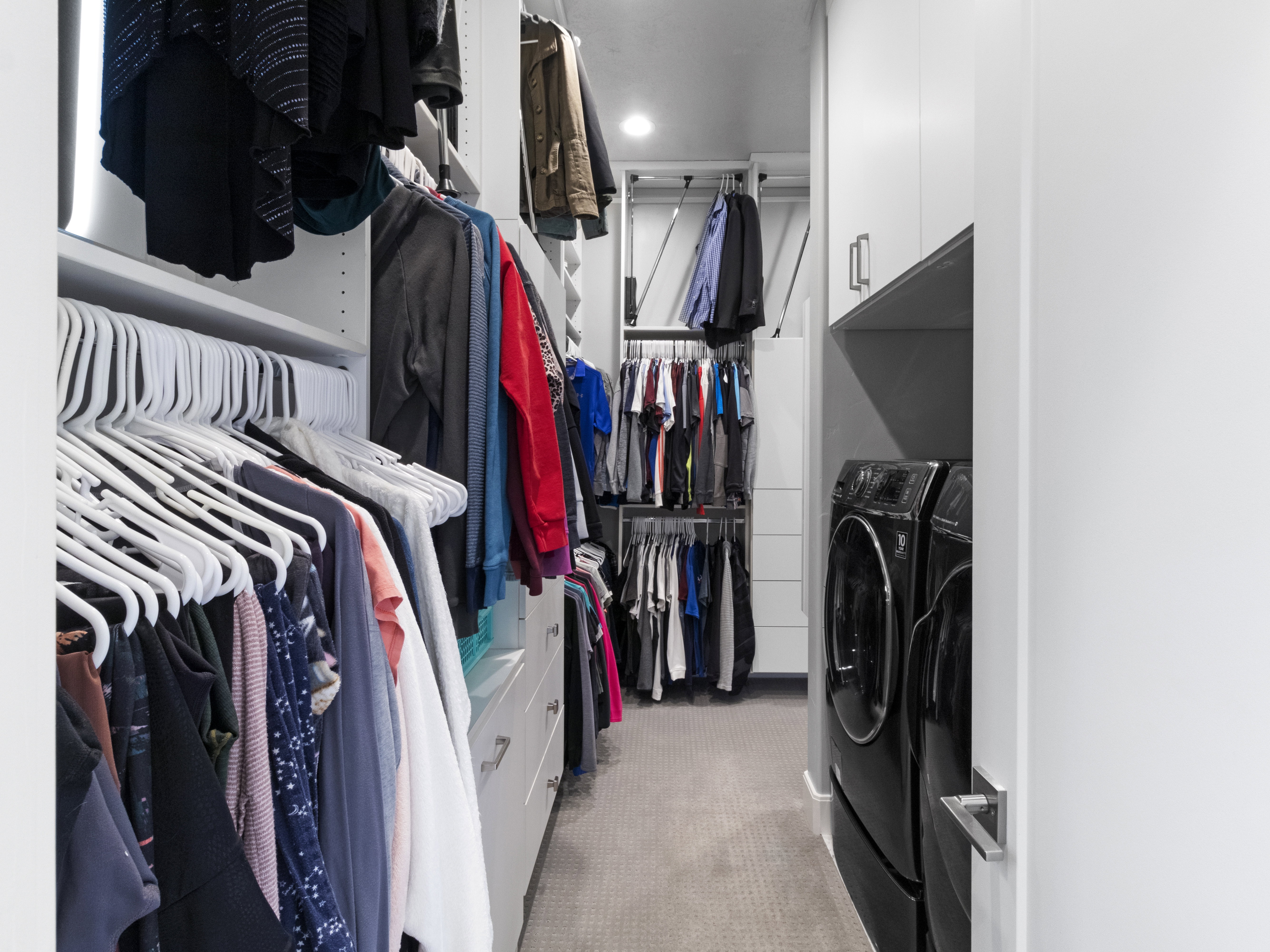 Walk in closet with light colored carpet and washing machine and clothes dryer