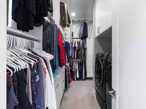 Walk in closet with light colored carpet and washing machine and clothes dryer