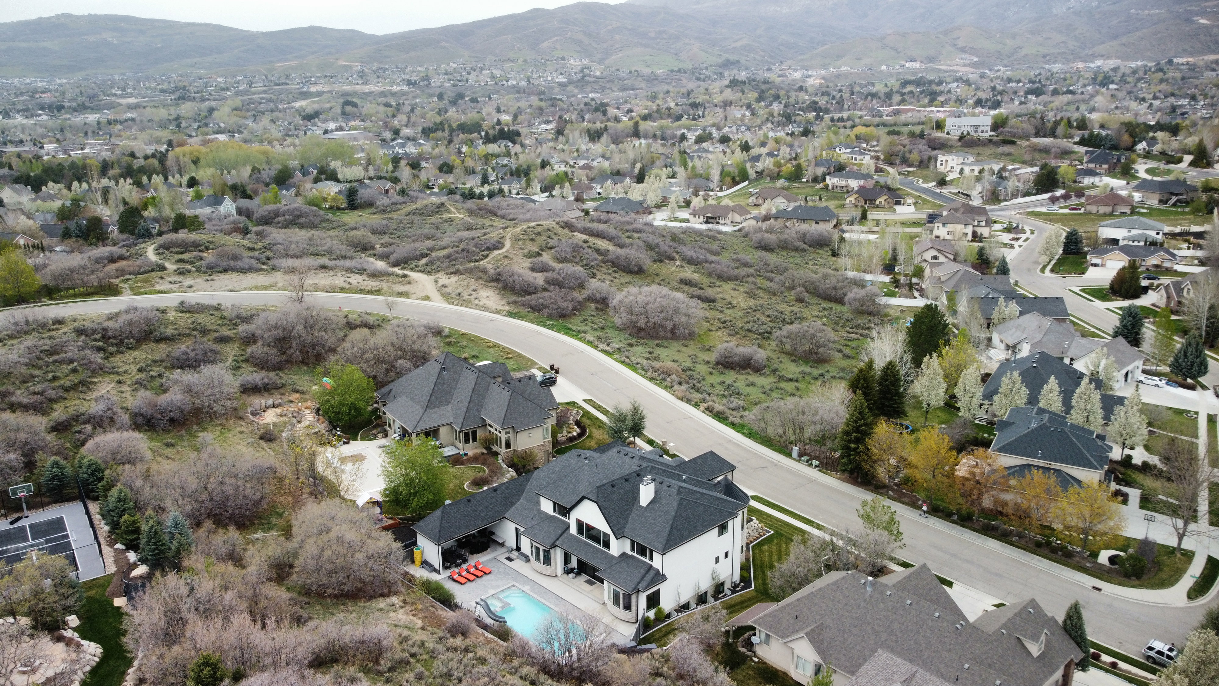 Aerial view of property and surrounding area with a mountainous background and nearby suburban area