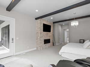 Bedroom featuring beamed ceiling, carpet, a stone fireplace, access to outside, and hanging lights