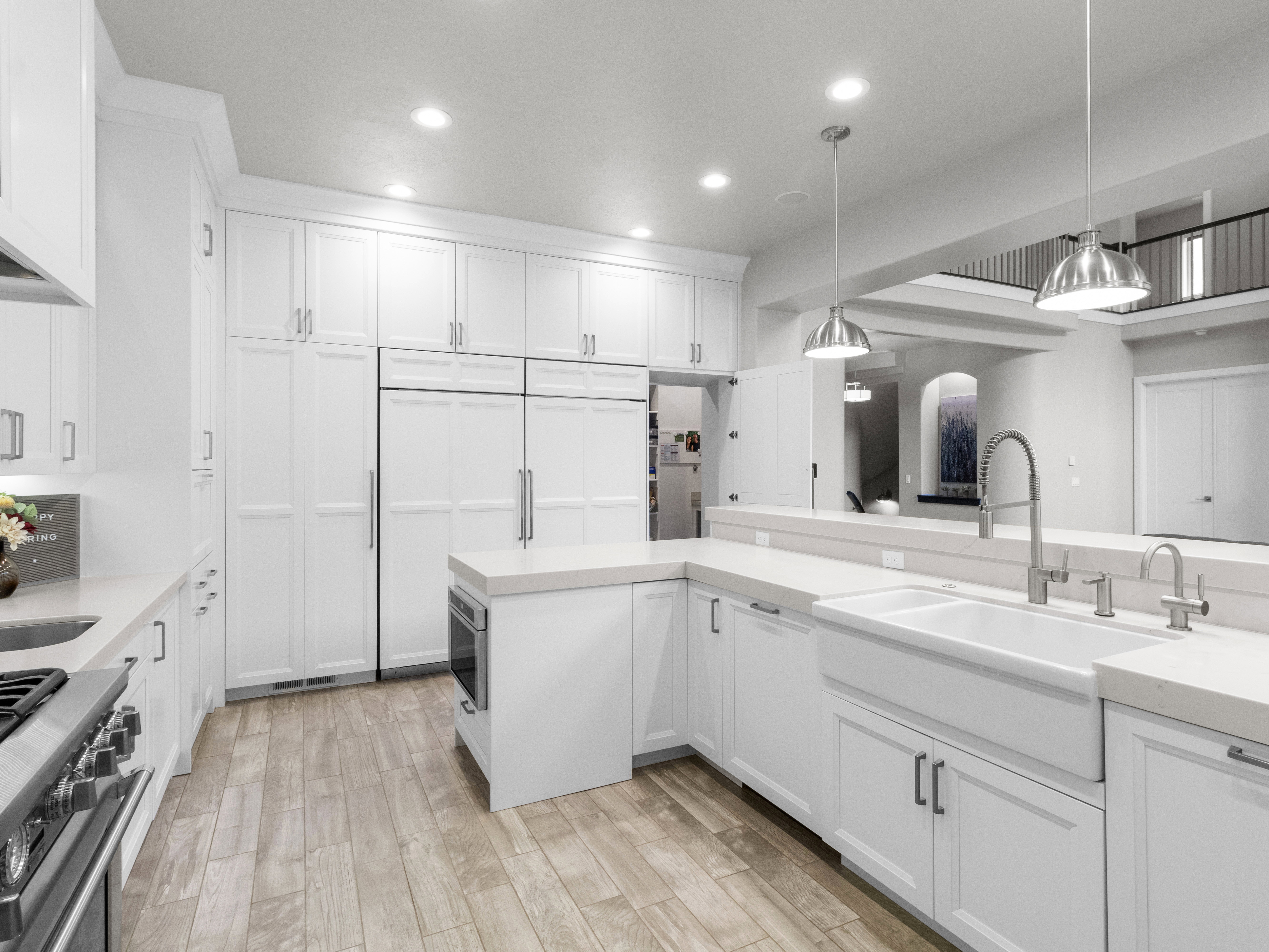 Kitchen with white cabinetry, stainless steel range, hanging light fixtures, and light wood-type flooring