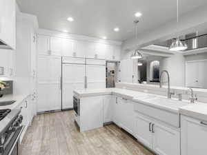 Kitchen with white cabinetry, stainless steel range, hanging light fixtures, and light wood-type flooring
