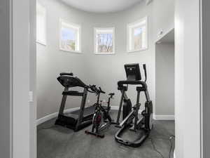 Workout room with plenty of natural light and dark colored carpet