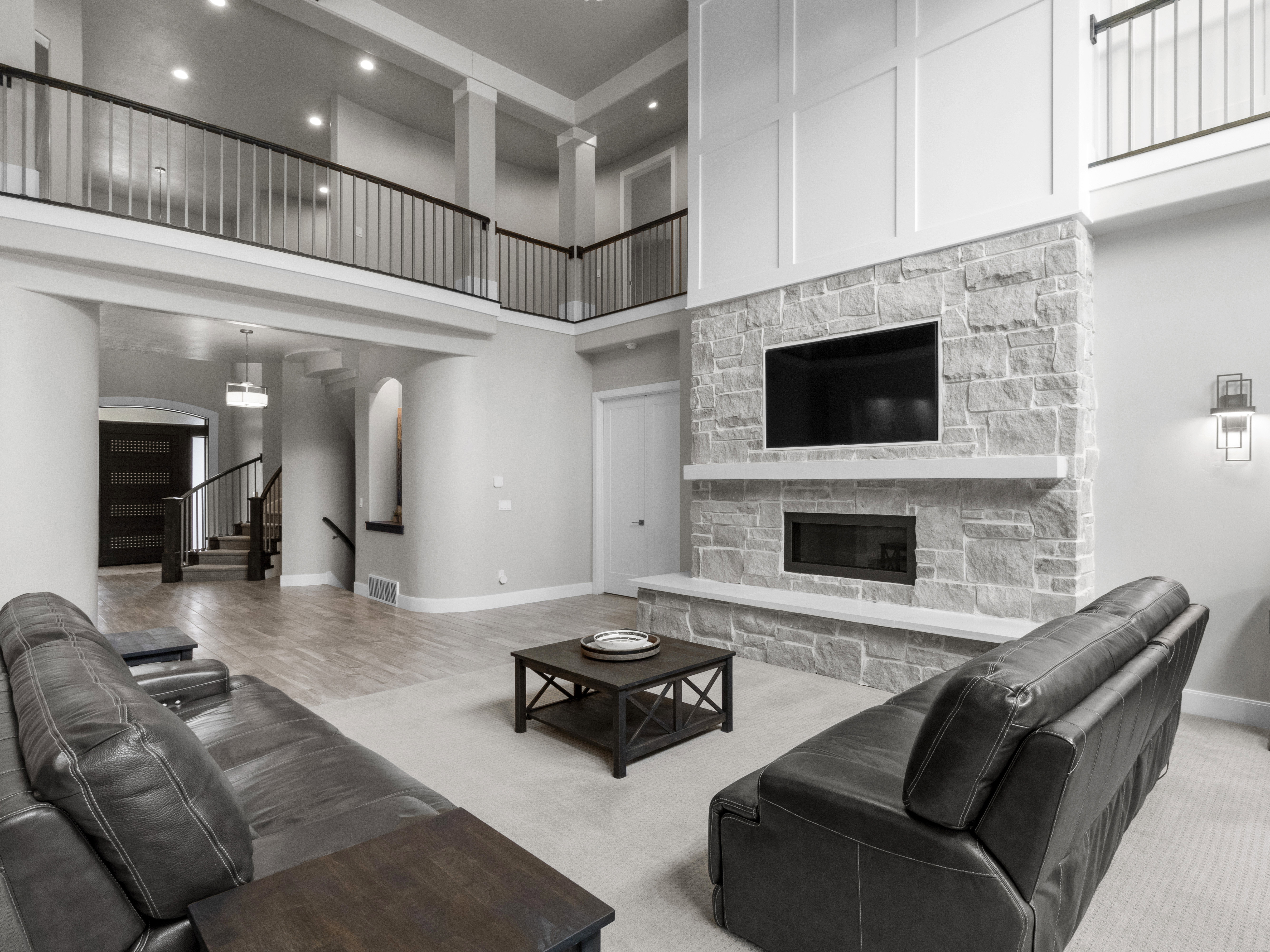Carpeted living room with a stone fireplace, arched walkways, and a high ceiling