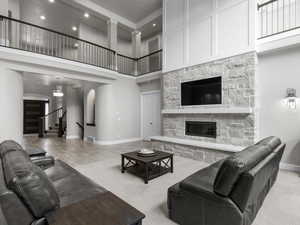 Carpeted living room with a stone fireplace, arched walkways, and a high ceiling
