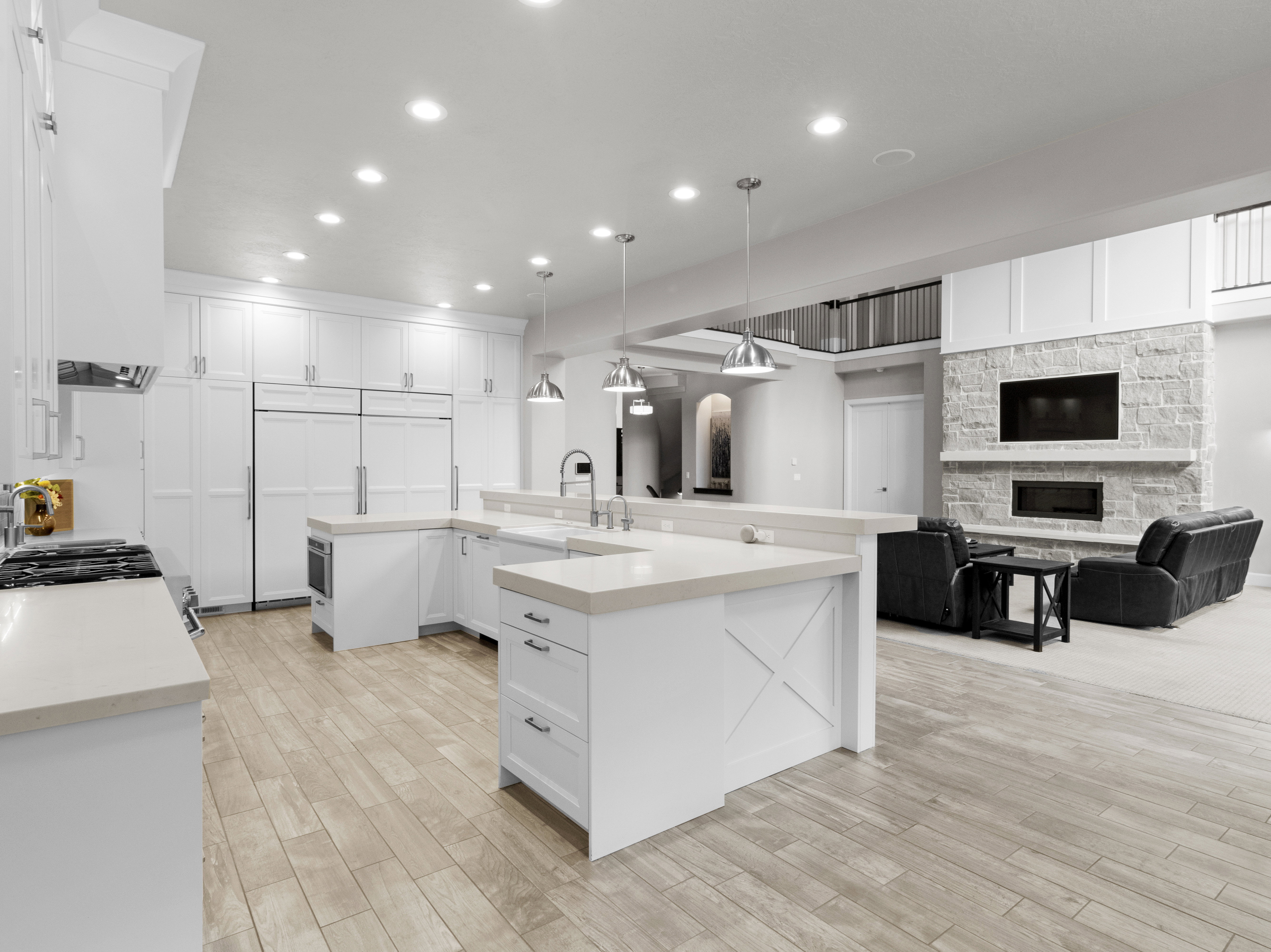 Kitchen with a stone fireplace, open floor plan, white cabinets, light wood-style floors, and hanging light fixtures