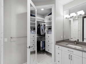 Bathroom with light marble finish flooring, vanity, and a spacious closet