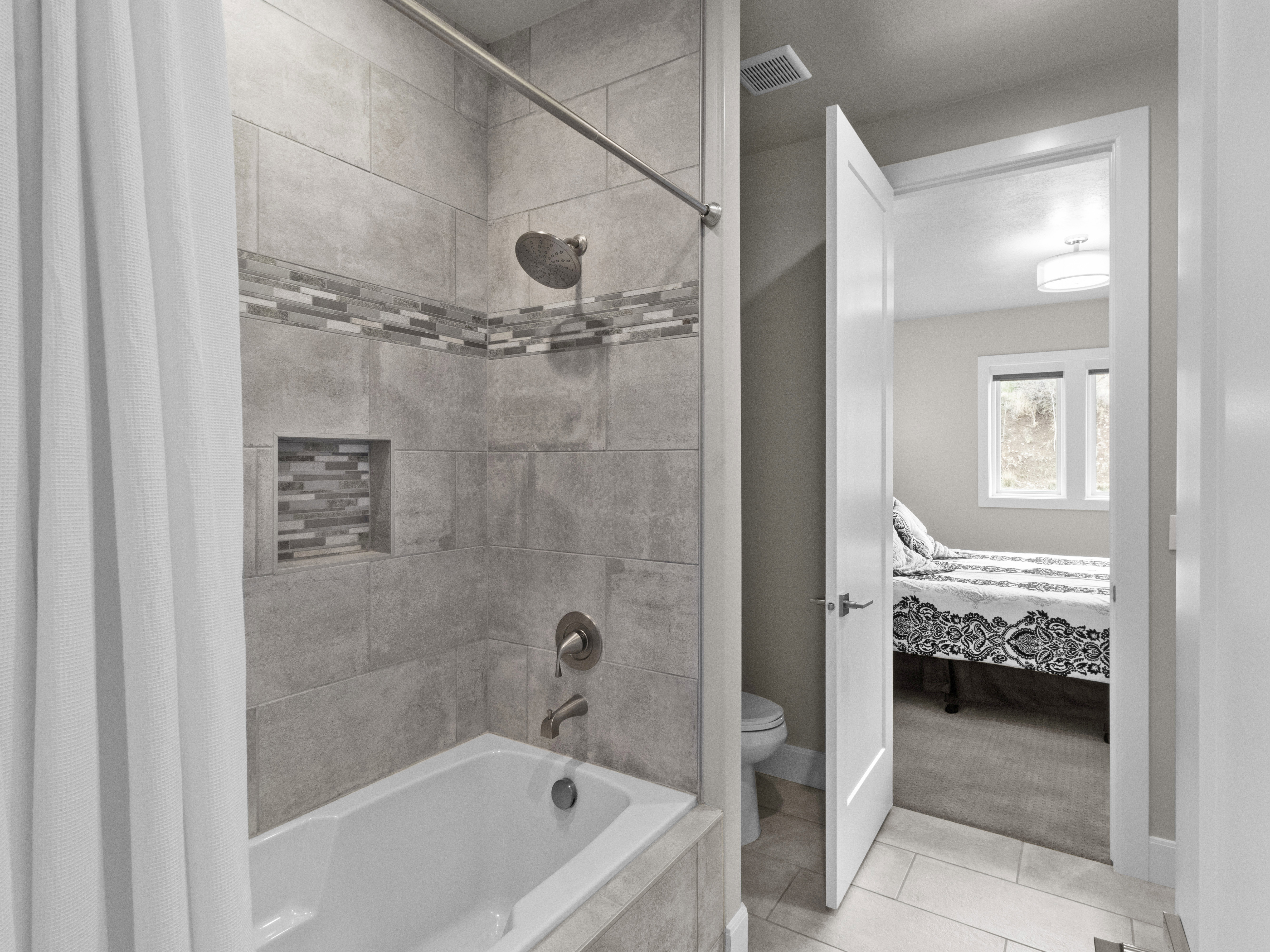 Full bathroom featuring tiled shower / bath combo, connected bathroom, light tile patterned floors, and light carpet