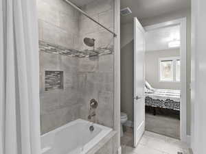 Full bathroom featuring tiled shower / bath combo, connected bathroom, light tile patterned floors, and light carpet