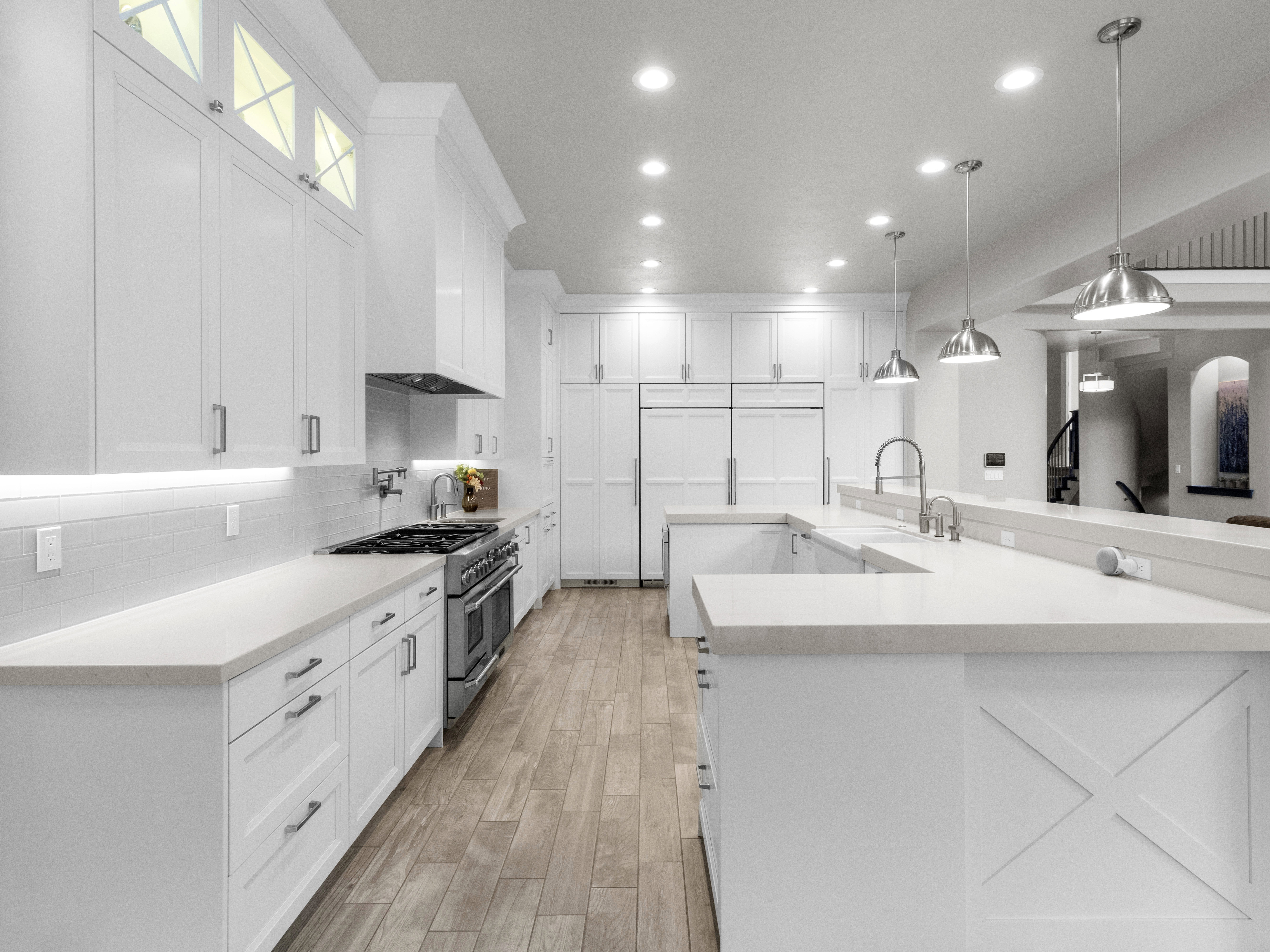 Kitchen featuring white cabinetry, double oven range, pendant lighting, and light wood-style flooring