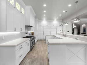 Kitchen featuring white cabinetry, double oven range, pendant lighting, and light wood-style flooring