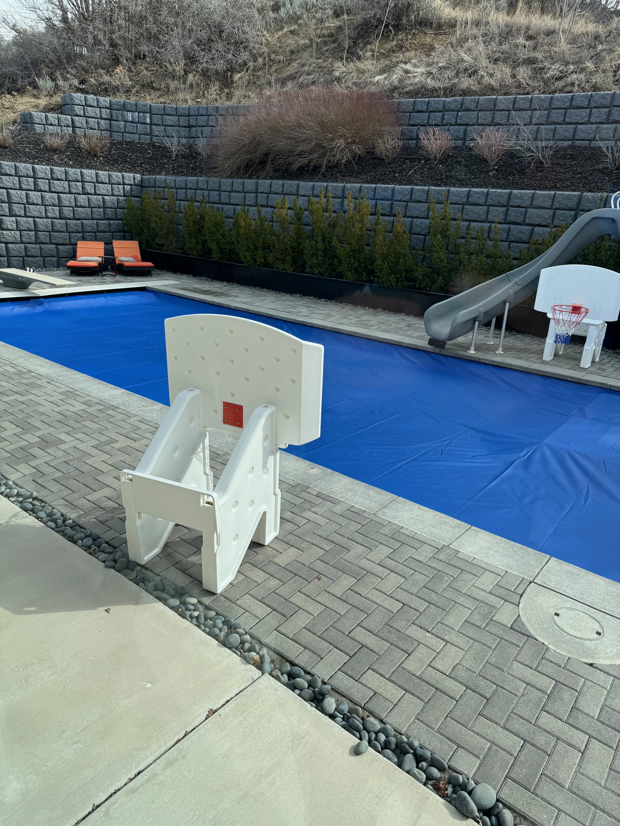 View of pool with a water slide, a fenced backyard, a diving board, and patio surround