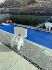 View of pool with a water slide, a fenced backyard, a diving board, and patio surround