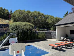 View of swimming pool with patio surround, a water slide, and outdoor lounge area