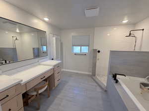 Full bathroom featuring a walk in shower, a garden tub, vanity, and light tile patterned floors