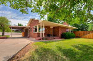 View of front of home featuring an attached carport, brick siding and front porch
