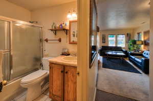 Apartment bathroom featuring vanity, enclosed tub / shower combo, light colored carpet, and a textured ceiling
