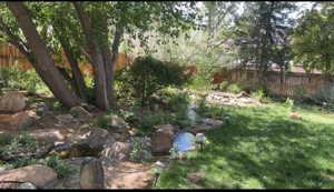 Fenced backyard featuring a garden pond