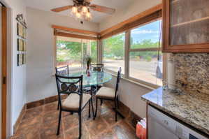 Dining area with a ceiling fan and dark stone finish floors, bright sunny windows
