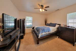 Apartment bedroom featuring light colored carpet and a ceiling fan