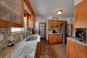 Kitchen featuring glass fronted cabinets, wood finish cabinets, stainless steel refrigerator, and Granite countertops