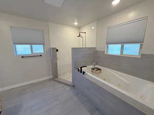 Bathroom with walk in shower, a jetted tub, plenty of natural light, tile patterned flooring, and recessed lighting