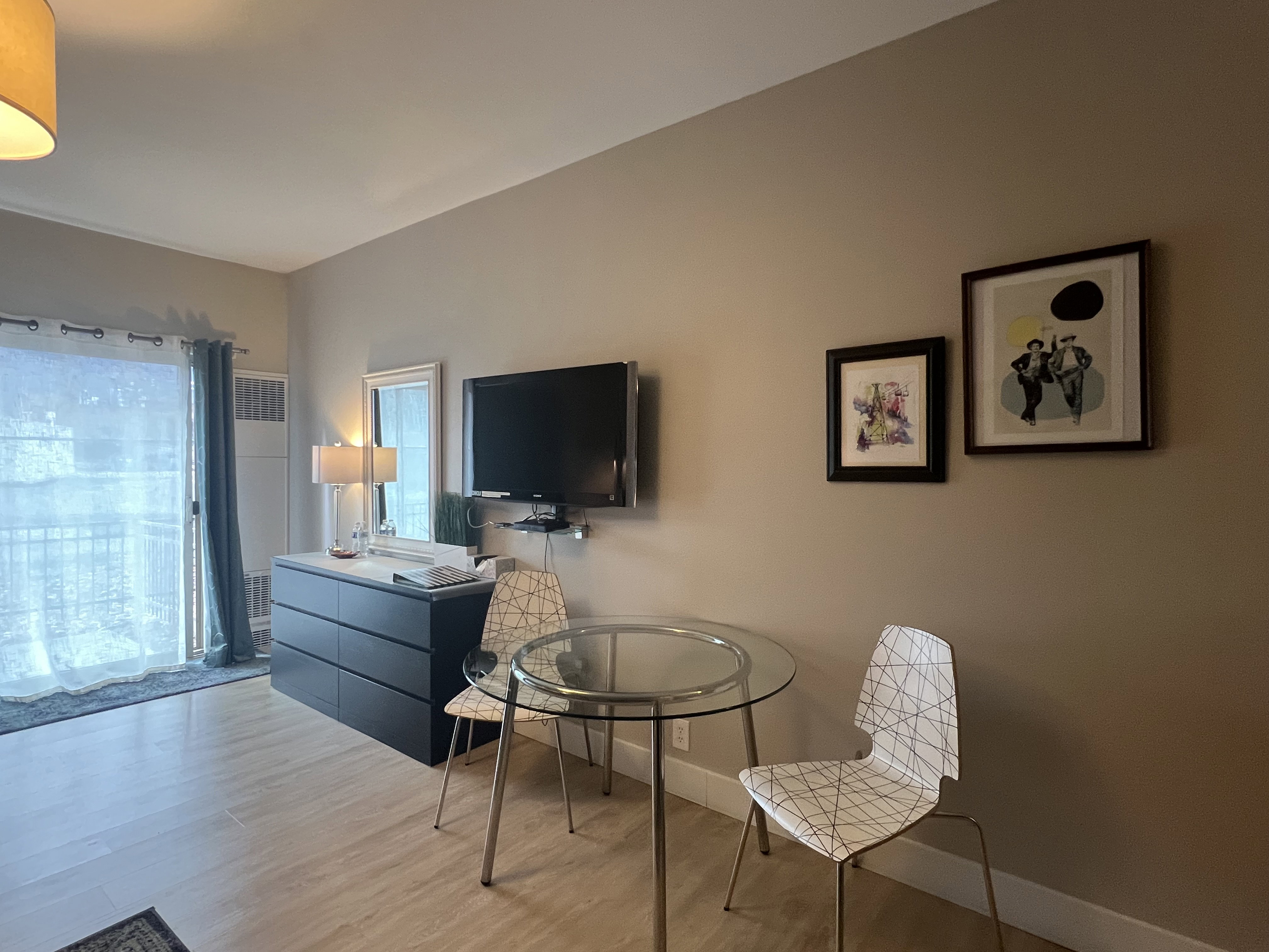 Small dining area, wall mounted TV, and dresser
