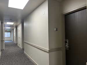 Hallway with dark carpet and a paneled ceiling