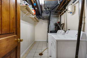 Laundry area with light tile patterned floors and washing machine and clothes dryer