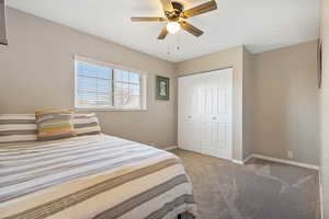 Bedroom featuring light colored carpet, a ceiling fan, and a closet