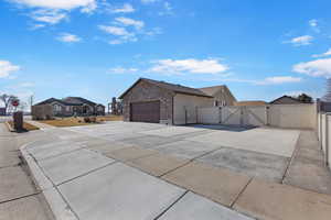 View of side of property with stone siding, a gate, concrete driveway, a residential view, and a garage