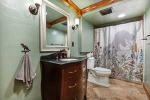 Downstairs full bath with curtained shower, vanity, and light stone finish flooring located in the basement
