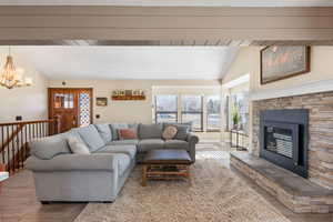 Living area with lofted ceiling, a fireplace, healthy amount of natural light, hanging lights, and wood finished floors