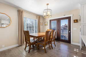 Dining space with light wood finished floors, a chandelier, plenty of natural light, and a textured ceiling