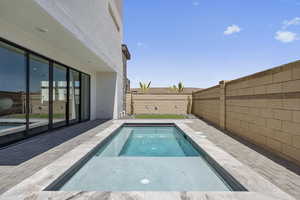 View of pool featuring patio surround, a fenced backyard, and a jacuzzi