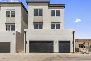 Contemporary home with stucco siding, a garage, and concrete driveway