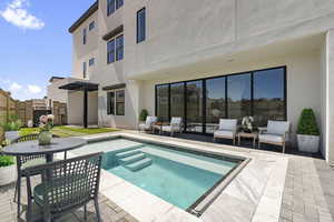Back of property with a patio area, stucco siding, a jacuzzi, a pergola, and outdoor dining space