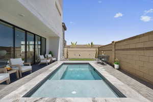 View of swimming pool featuring patio surround and a fenced backyard
